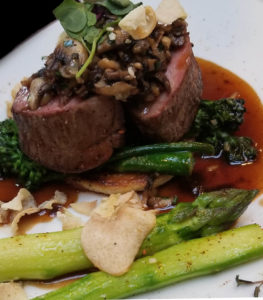 deconstructed venison wellington—puffed pastry, mushrooms, broccolini with elephant garlic, white and green asparagus, and veal reduction